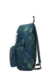 Texturerad ryggsäck i mörkgrön med ett kamouflagemönster. Har ett stort huvudfack, sidoficka och vit logotyp.