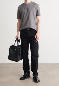 Grå t-shirt med kort ärm och "BOSS"-logotyp, svarta jeans, svart läderväska och svarta skor. Enkelt design med minimala accenter.