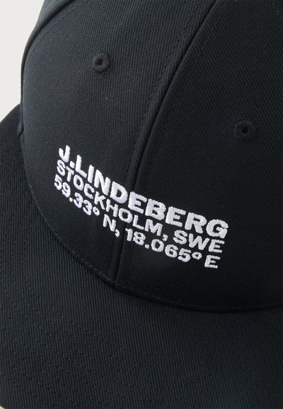 Casquette noire avec texte brodé blanc affichant "J. Lindeberg Stockholm, SWE" et les coordonnées "59.333° N, 18.065° E" sur le panneau avant.