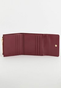 Portefeuille en cuir bordeaux avec plusieurs emplacements pour cartes, un compartiment zippé et une fermeture à bouton-pression ; texture lisse avec marquage en relief.