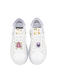 Le sneakers bianchi presentano accenti dorati, un design con cordini, dettagli viola sulla linguetta e decorazioni di gioielli: una rana rosa e una gemma viola.