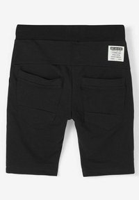 Shorts en coton noirs avec une taille douce, deux poches arrière et une petite étiquette sur la taille affichant les instructions d'entretien et le logo.