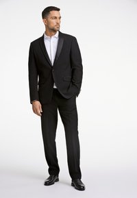 Czarny garnitur z satynowym klapą z szpicem, dopasowany fason i dwie przednie kieszenie. W zestawie z białą koszulą na guziki i czarnymi eleganckimi butami.