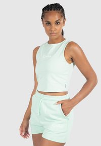 Conjunto de dos piezas en verde menta que incluye un top corto y pantalones cortos a juego. Tela suave con una textura lisa y detalle de bolsillo en la parte frontal de los pantalones cortos.
