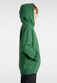 Felpa verde con cappuccio, tasca a marsupio, maniche lunghe e vestibilità comoda. Texture liscia e design semplice senza motivi visibili.