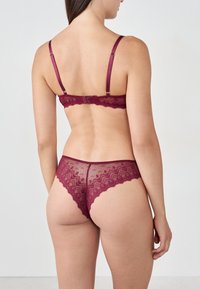 Burgundy lace lingerie set featuring adjustable straps, scalloped edges, and a geometric pattern on the back of the panties.