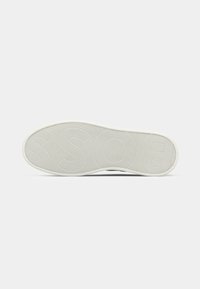 Semelle d'une chaussure blanche avec une surface en caoutchouc texturée et le mot BOSS embossé sur la semelle.