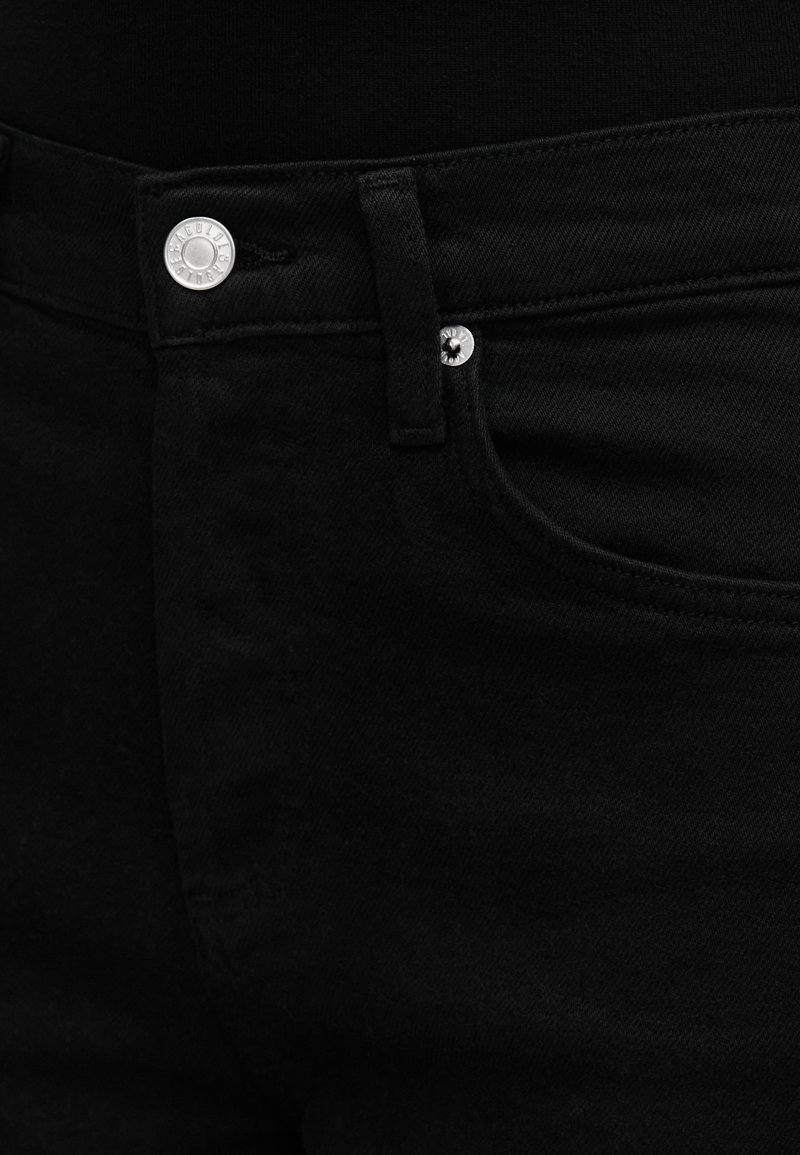 Jean denim noir avec une texture lisse, doté d'une fermeture à bouton argenté et d'une poche avant. Les coutures sont visibles le long des seams.