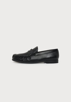 Loafer negru din piele cu toc jos, cusătură de tip mocasin la vârf și bandă clasică penny, prezentat din profil pe un fundal alb simplu.