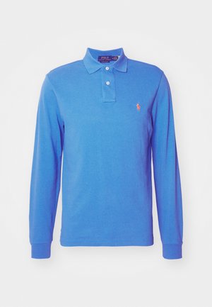 Garais piedurkņu polo krekls spilgti zilā kokvilnā, ar trīs pogu atloku un izšūtu logotipu kontrastējošā oranžā krāsā uz krūtīm.