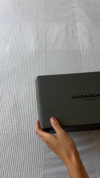 Szürke, matt felületű téglalap alakú doboz, amelyen fekete színnel szerepel a "VAGABOND" felirat a tetején. Az alatta található puha textúrájú felület világos színű és mintákkal díszített.