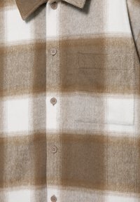Brun och vit rutig skjorta i mjukt flanelltyg, med spetsig krage, sex knappar och en vänster bröstficka.