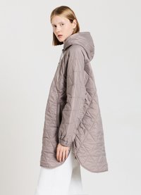 Giacca imbottita leggera in morbido taupe con cappuccio, dotata di polsini elasticizzati e un orlo leggermente curvo per una lunghezza aggiuntiva.