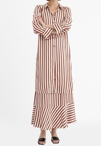 Lång, randig klänning i krämfärgad och bordeaux, med knäppning fram, långa ärmar och en vågig nederdel. Snyggt tyg med avslappnad passform.