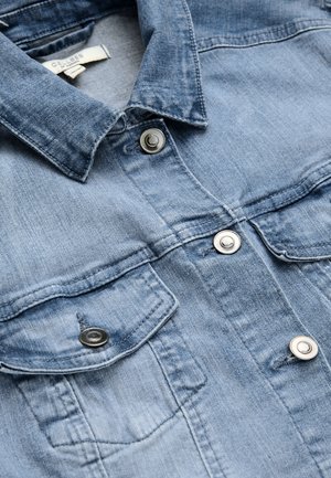 Hellblaue Jeansjacke mit metallenen Druckknöpfen, spitzem Kragen, zwei vorderen Klappentaschen und sichtbaren Nahtdetails.