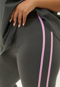 Grå leggings gjorda av stretchigt material, med två vertikala rosa ränder på sidan. Slät yta med en åtsittande design.