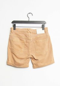 Shorts en denim beige avec une taille, des manches retournées et deux poches arrière. Ils présentent des détails de coutures et une étiquette à la taille.