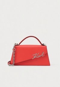 Punane nahast käekott struktureeritud kujuga, hõbedase kettkäepidemega ja esiküljel silmatorkava hõbedase "Karl" logoga.