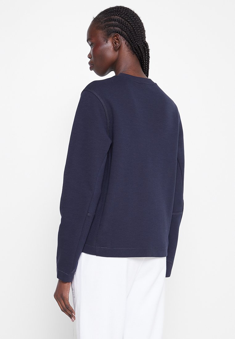 Marineblaues Sweatshirt aus einem weichen Strickstoff mit Rundhalsausschnitt und langen Ärmeln, sichtbaren Nähten an den Säumen und einer lockeren Passform.