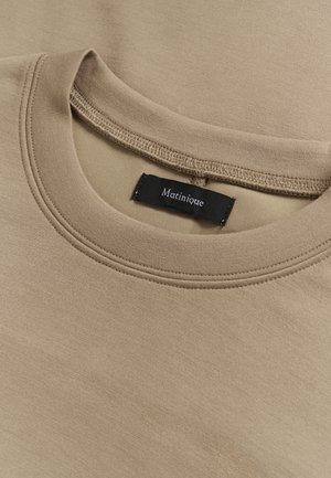 Camiseta beige de cuello redondo con costura doble en el cuello y etiqueta de marca negra "Matinique" cosida en el interior del cuello.