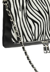 Borsa a tracolla con motivo zebra che combina pelle nera e pelliccia sintetica, dotata di una tracolla in catena argentata e doppi cursori per la cerniera.