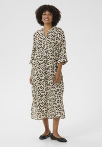 Vestido de longitud a la rodilla con estampado de leopardo, escote en V y mangas de tres cuartos. Hecho de una tela ligera, presenta cierres de botón y aberturas laterales.