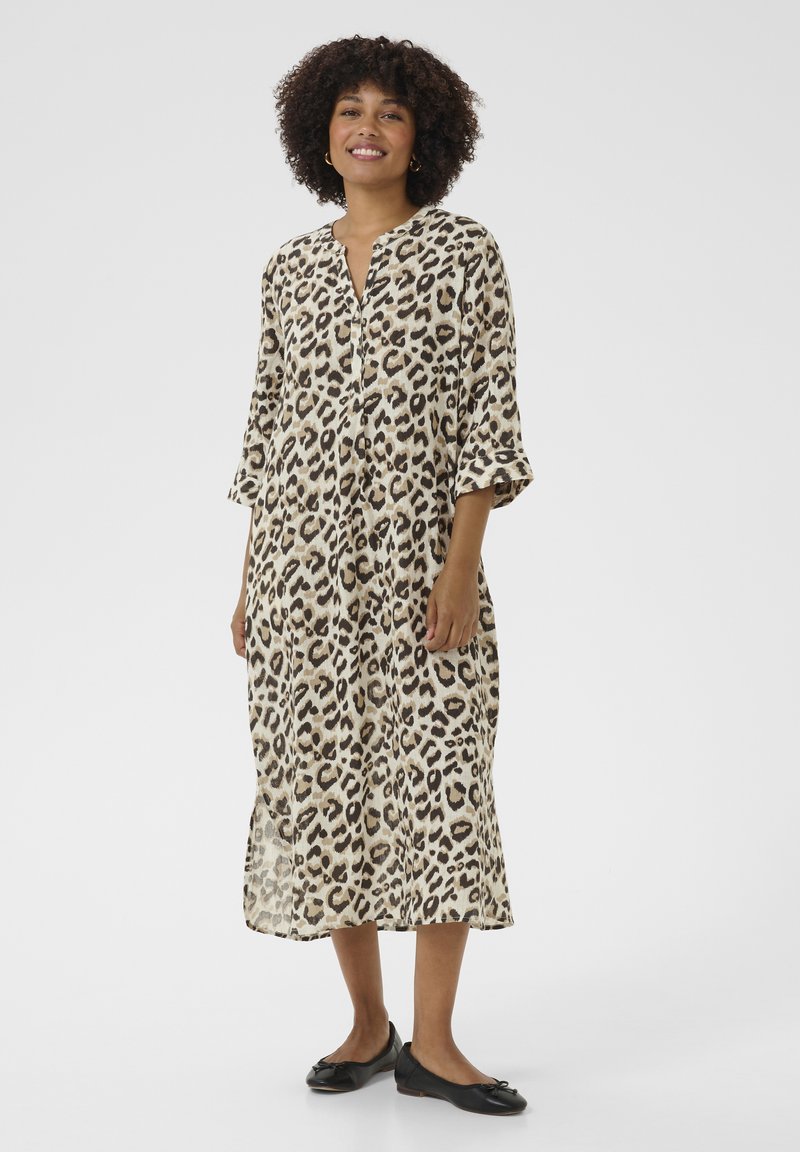 Vestido de longitud a la rodilla con estampado de leopardo, escote en V y mangas de tres cuartos. Hecho de una tela ligera, presenta cierres de botón y aberturas laterales.