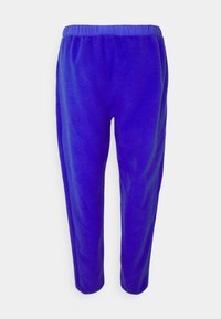 Lila fleecebyxor med elastisk midja, som har en mjuk, texturerad yta och avsmalnande benutformning. Slät innerfoder för komfort.