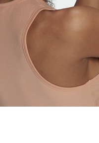 Jasnoróżowy prążkowany top na ramiączkach z okrągłym dekoltem, eksponujący gładką teksturę skóry w okolicach ramion i górnej części pleców.