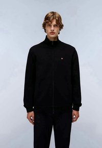 Jaqueta preta com fecho zip, com colarinho alto, feita de material suave. Apresenta um pequeno logótipo no peito e punhos canelados. Design minimalista.