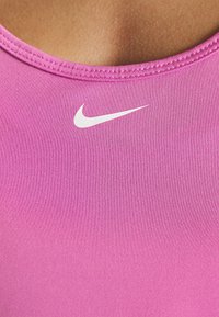 Gros plan d'un haut de sport rose avec un logo Nike swoosh blanc près de l'encolure.