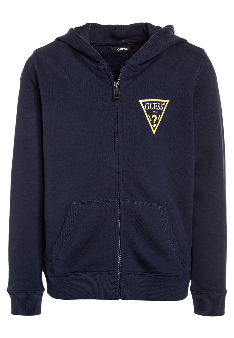 Hoodie zippé marine en mélange de coton. Il présente un logo triangulaire jaune "GUESS" sur la poitrine gauche et des poches kangourou. Texture douce.