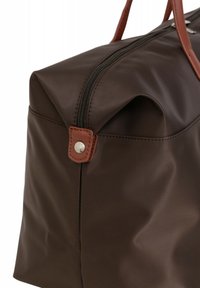 Borsa da viaggio in tessuto marrone con dettagli in pelle marrone, chiusura con zip superiore e forma arrotondata con bordi piegati. Dettagli in hardware argentato.