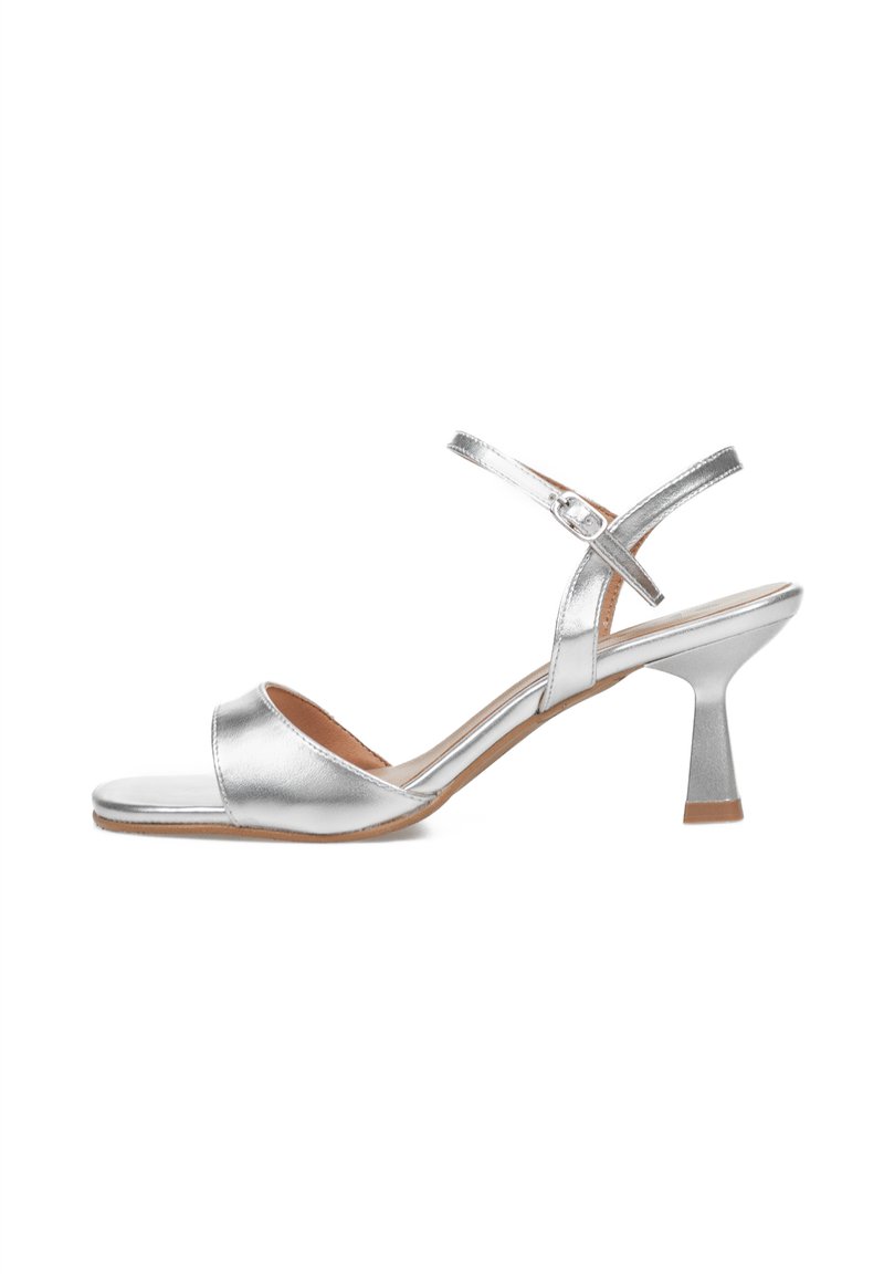 Sandalias de tacón alto metálicas plateadas con punta abierta, correa en el tobillo y un tacón de bloque contorneado. Acabado suave con un brillo sutil.