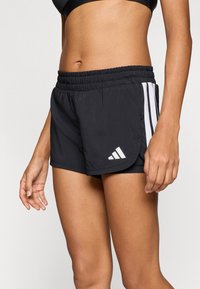 Čierne atletické šortky z ľahkej tkaniny s bielymi bočnými pruhmi, elastickým pásom a malým logom na leme.