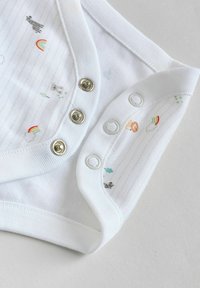 Bodysuit en coton blanc avec des imprimés d'animaux colorés et d'arc-en-ciel, boutons-pression et bords côtelés doux. Texture rayée subtile visible.