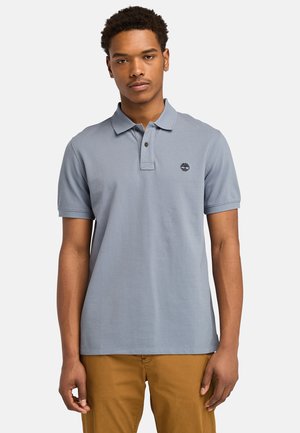 Light blue polo shirt with a collar, two buttons, and a small black logo on the left chest. Short sleeves with a straight hem.
