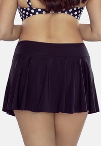 Fustă scurtă neagră cu design plisat, talie lată și pantaloni scurți ajustați dedesubt. Textură netedă, realizată dintr-un material flexibil.