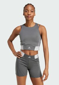 Gray athletic crop top with layered straps, fitted design, and white accents; paired with matching high-waisted shorts featuring seams and logo.