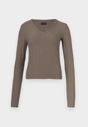 Langærmet, ribstrikket top i en dæmpet brun farve. V-udskæring med en tætsiddende silhuet. Blød tekstur, velegnet til lag-på-lag. Minimalistisk stil.
