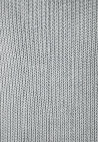 Lichtgrijze gebreide stof met een verticale ribbelstructuur. Zachte, strakke steken creëren een uniforme, gladde uitstraling.