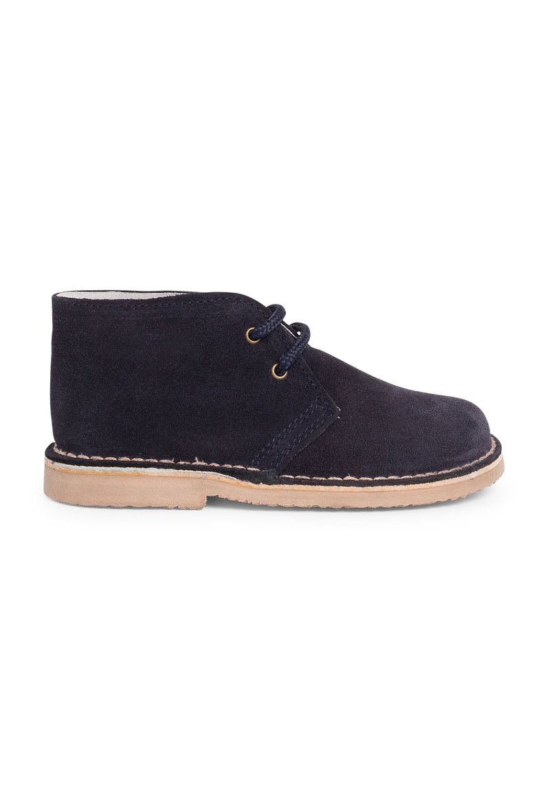 Bota de ante azul marino con suela de goma marrón claro, punta redonda y diseño con cordones que presenta dos ojales y costuras en contraste.