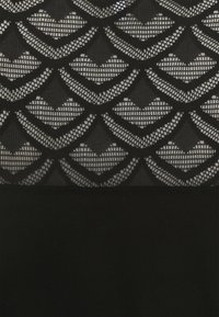 Svart tyg med ett geometriskt spetsmönster som har upprepande diamant- och chevronformer över en genomskinlig bakgrund.