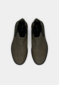 Olivgrüne Leder-Slipper mit glatter Oberfläche, elastischen Seitenpanelen und schwarzen Gummisohlen. Minimalistisches Design mit runder Zehenform.