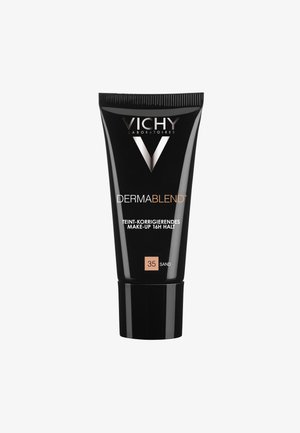 Black plastic tube with a matte finish, featuring silver logo and text. Size marked as 35 Sand, indicates foundation for correcting skin tone.