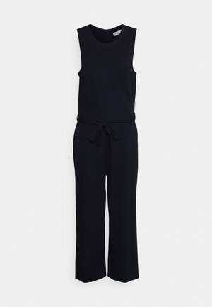 Combinaison noire sans manches avec encolure ronde, ceinture à la taille, poche poitrine et pantalon à jambes larges sur un fond clair uni.