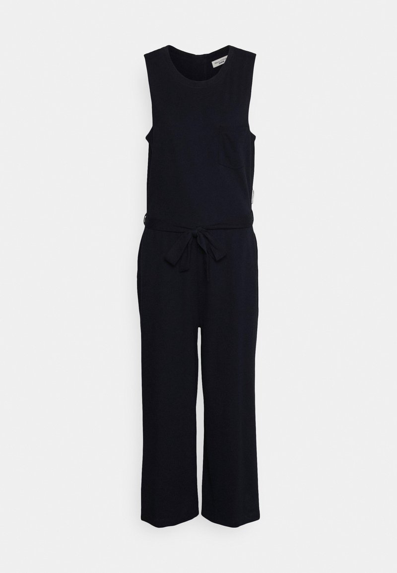 Combinaison noire sans manches avec encolure ronde, ceinture à la taille, poche poitrine et pantalon à jambes larges sur un fond clair uni.