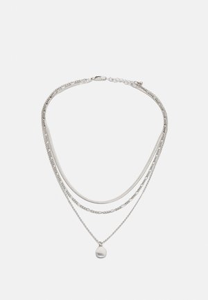 Silver layered necklace featuring multiple chain styles, including a smooth chain and a beaded chain, with a small circular pendant.