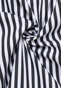 Tessuto a righe bianche e nere, con una texture liscia e linee verticali uniformemente distanziate, attorcigliato saldamente in una formazione circolare.