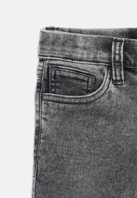 Melnas denim bikses ar nolietu, izbalējušu tekstūru, ar standarta jostu, mazu priekšējo kabatu un kontrastējošiem šuvju elementiem.